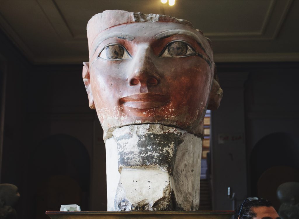 A big head of a statue sitting on a pedestal.
